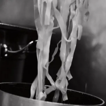 Tagliatelle fresche sollevate dalla pentola, in bianco e nero