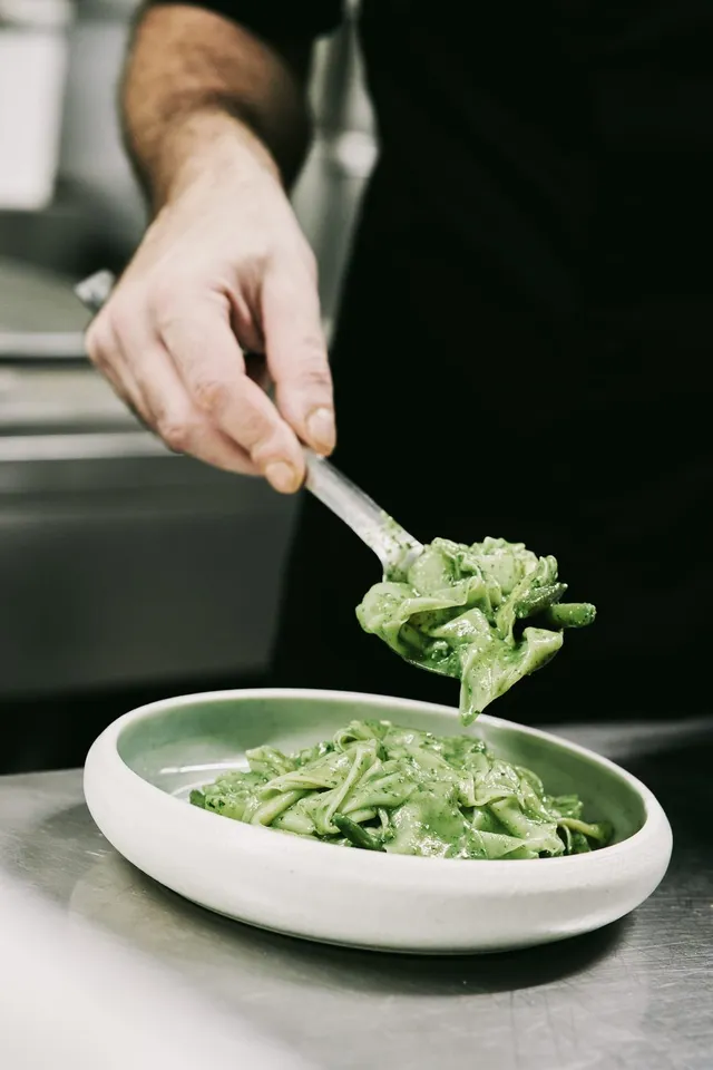 Un cucchiaio serve la pasta al pesto con i fagiolini