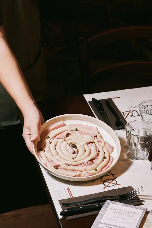 Un piatto di mortadella con crema e capperi servito al tavolo