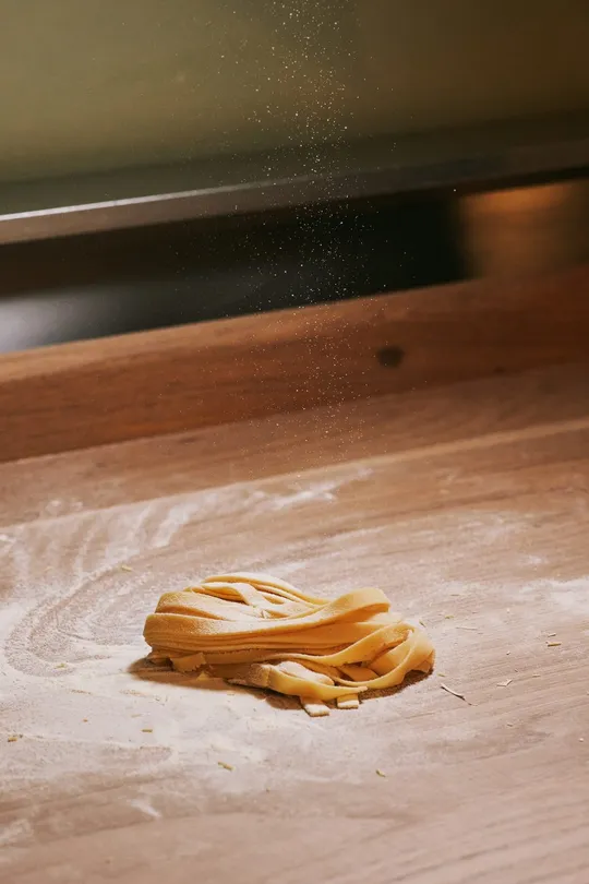 Un nido di tagliatelle fresche sotto una pioggia di farina