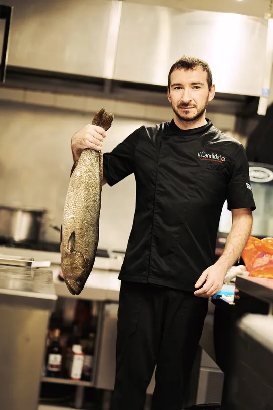 Il cuoco mostra un pesce intero appena arrivato