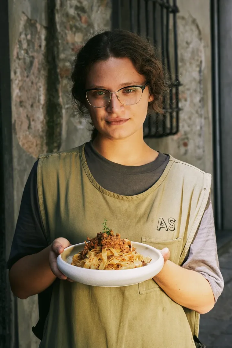 Una cameriera mostra un piatto di tagliatelle al ragù